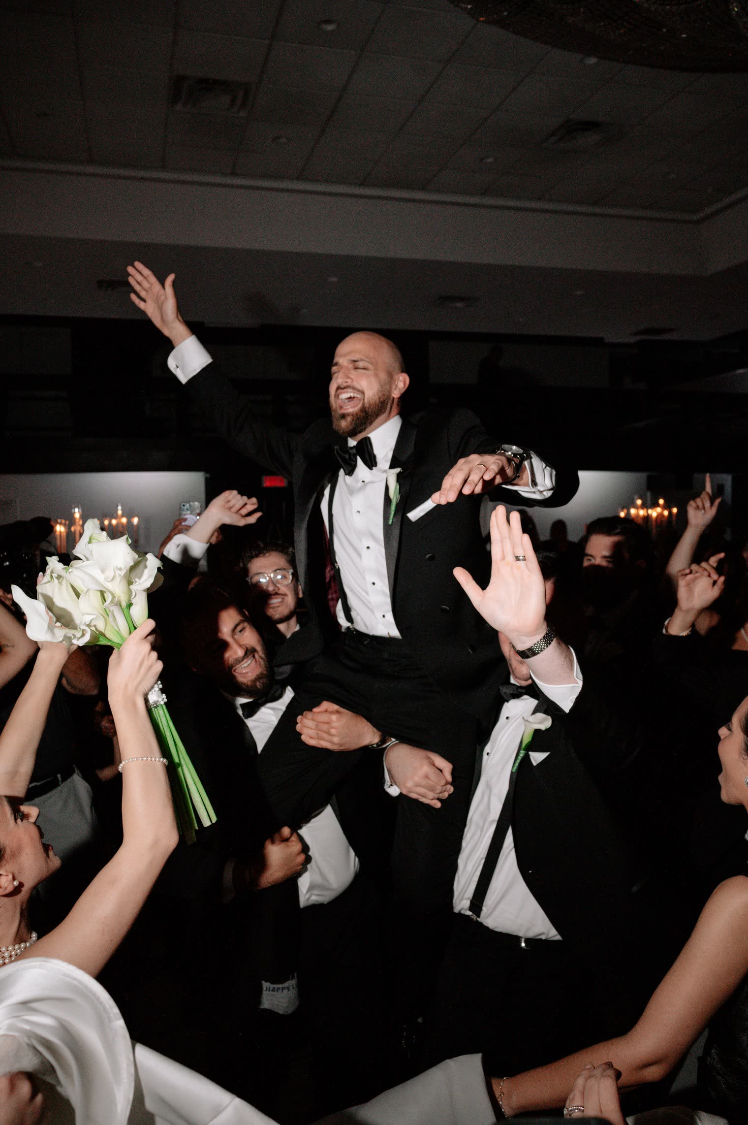 Groom lifted on his friends' shoulders above a cheering dance floor