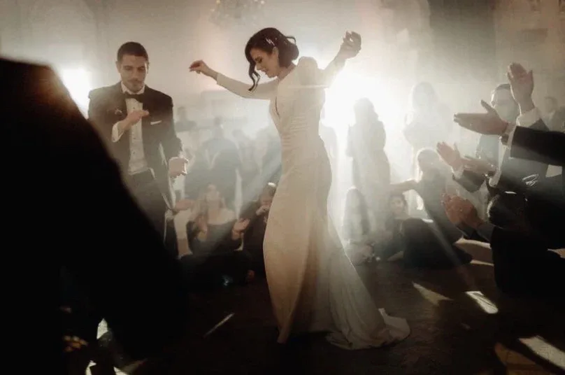 Bride dancing in a beam of light, surrounded by seated and clapping guests at Théâtre St-James